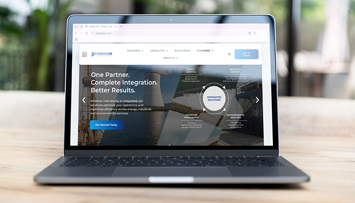 Computadora portátil mostrando la página de inicio de un sitio web corporativo con encabezado, texto descriptivo y llamada a la acción.
