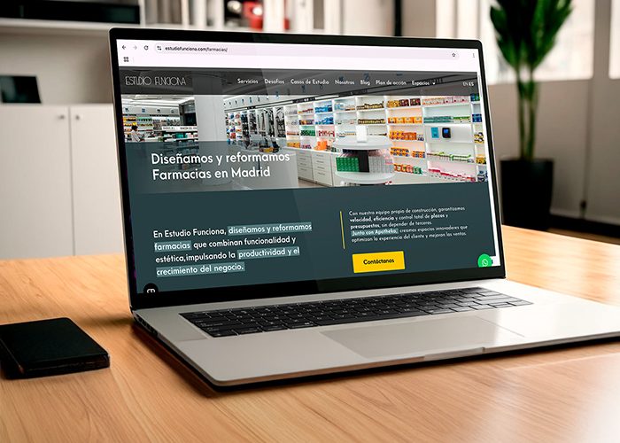 Computadora portátil sobre un escritorio mostrando la página web de Estudio Funciona con imagen de estanterías y contenido informativo del estudio.