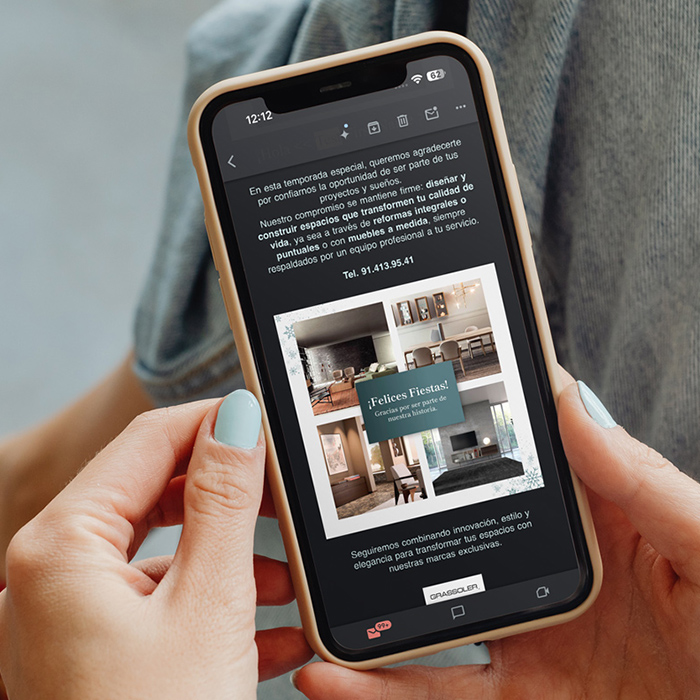 Persona sosteniendo un teléfono móvil con una pantalla de contenido visual de interiores y diseño arquitectónico.